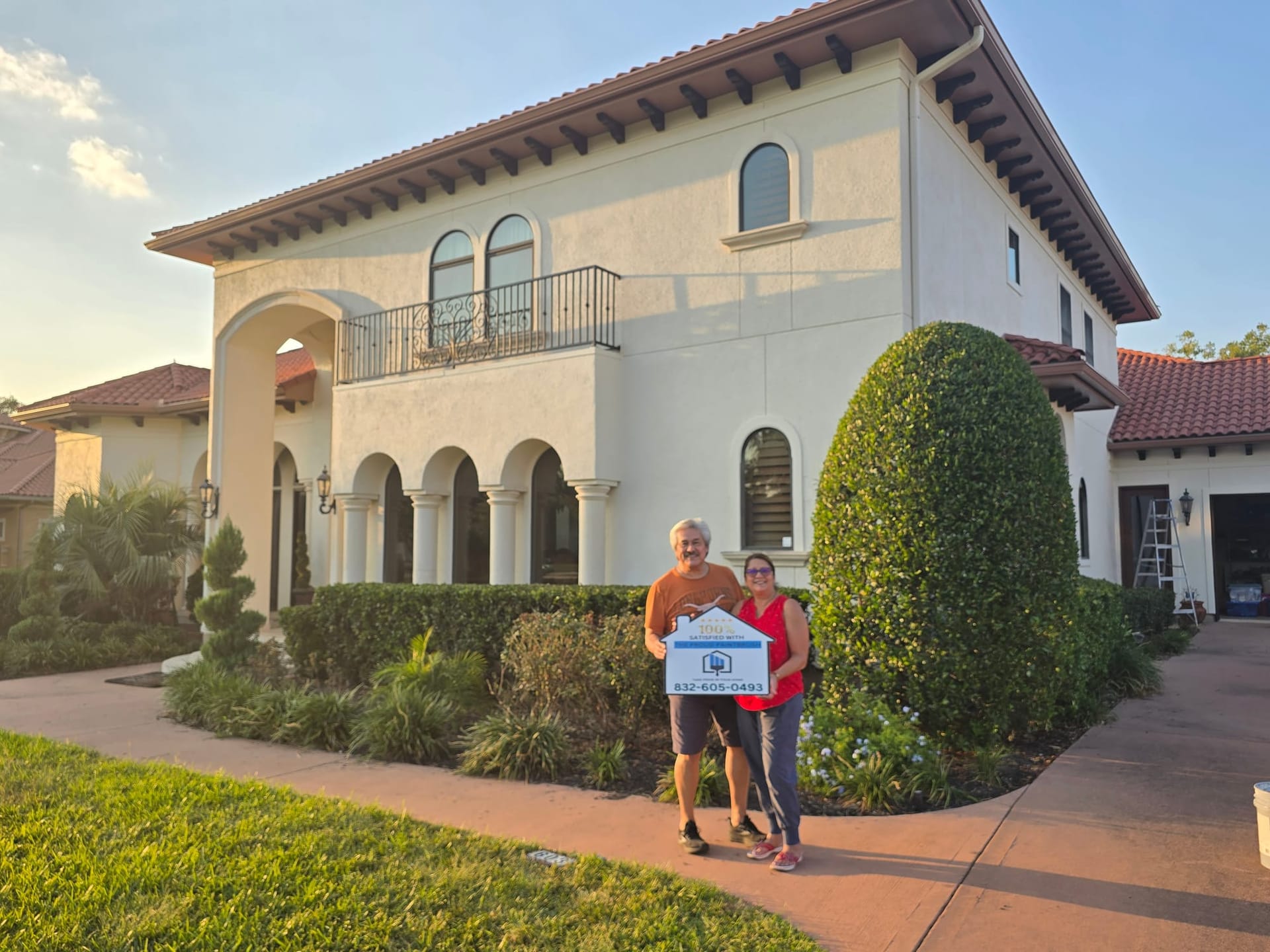 Happy homeowners in front of their freshly painted Mediterranean-style home in Sugar Land, TX