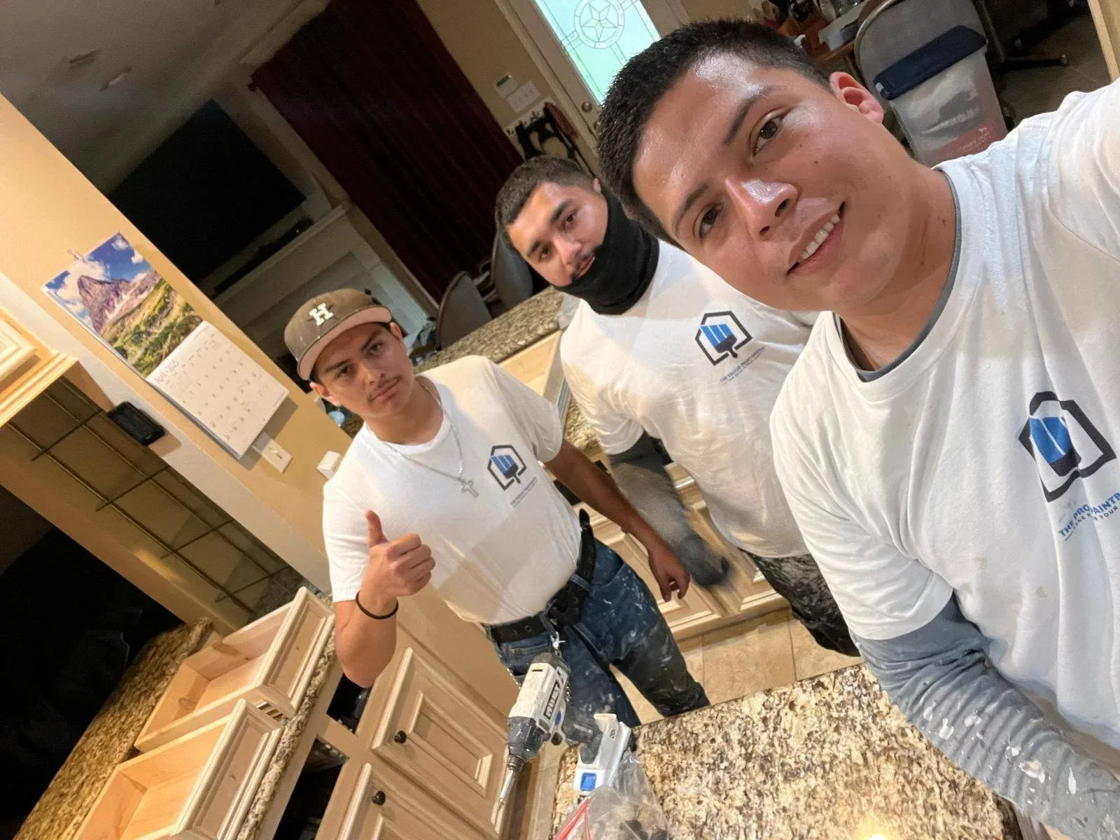Three professional painters prepping kitchen cabinets for painting in Katy, Texas