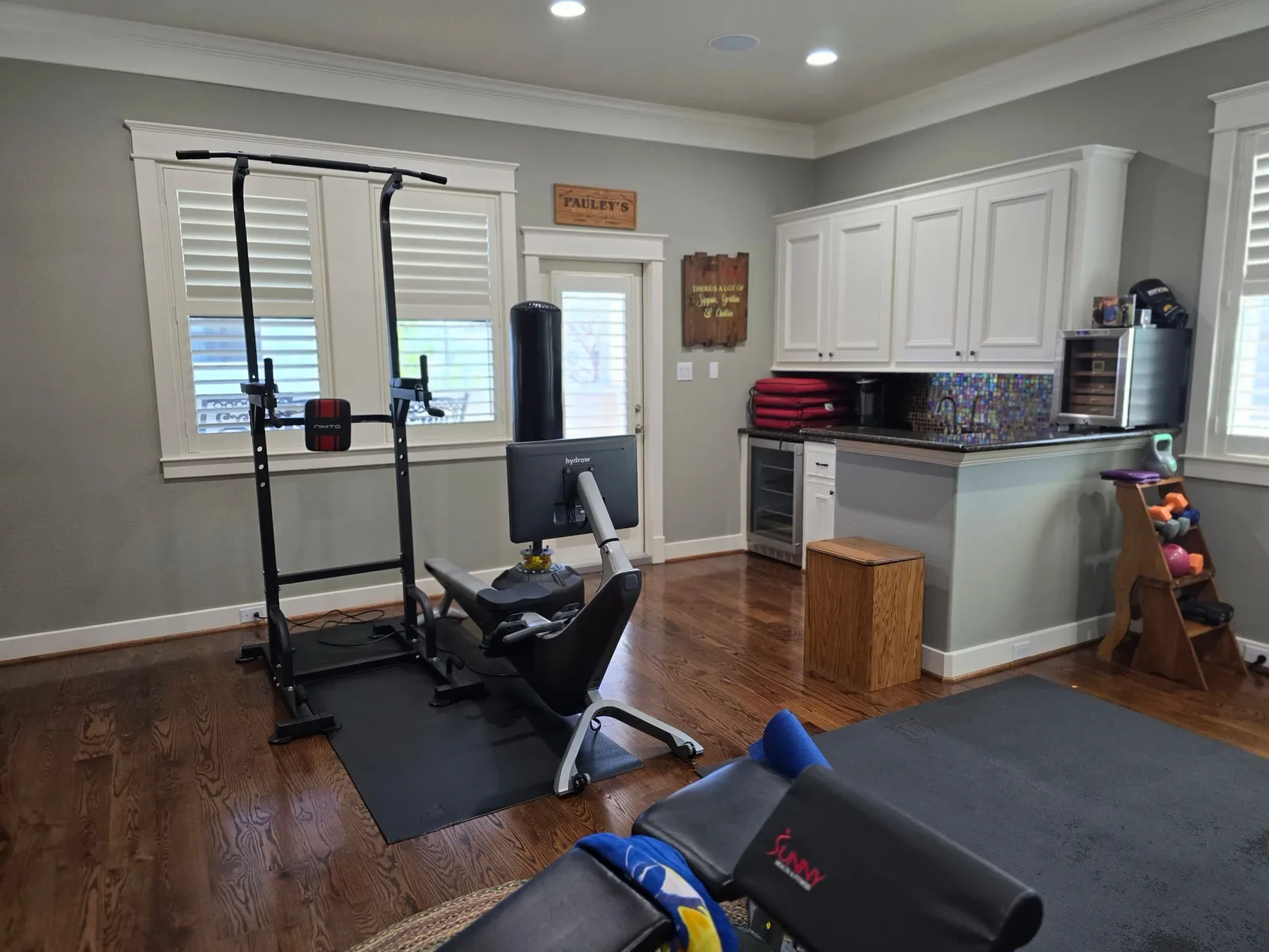 Fresh interior painting in a Fulshear TX home gym with smooth gray walls, white trim, and hardwood floors