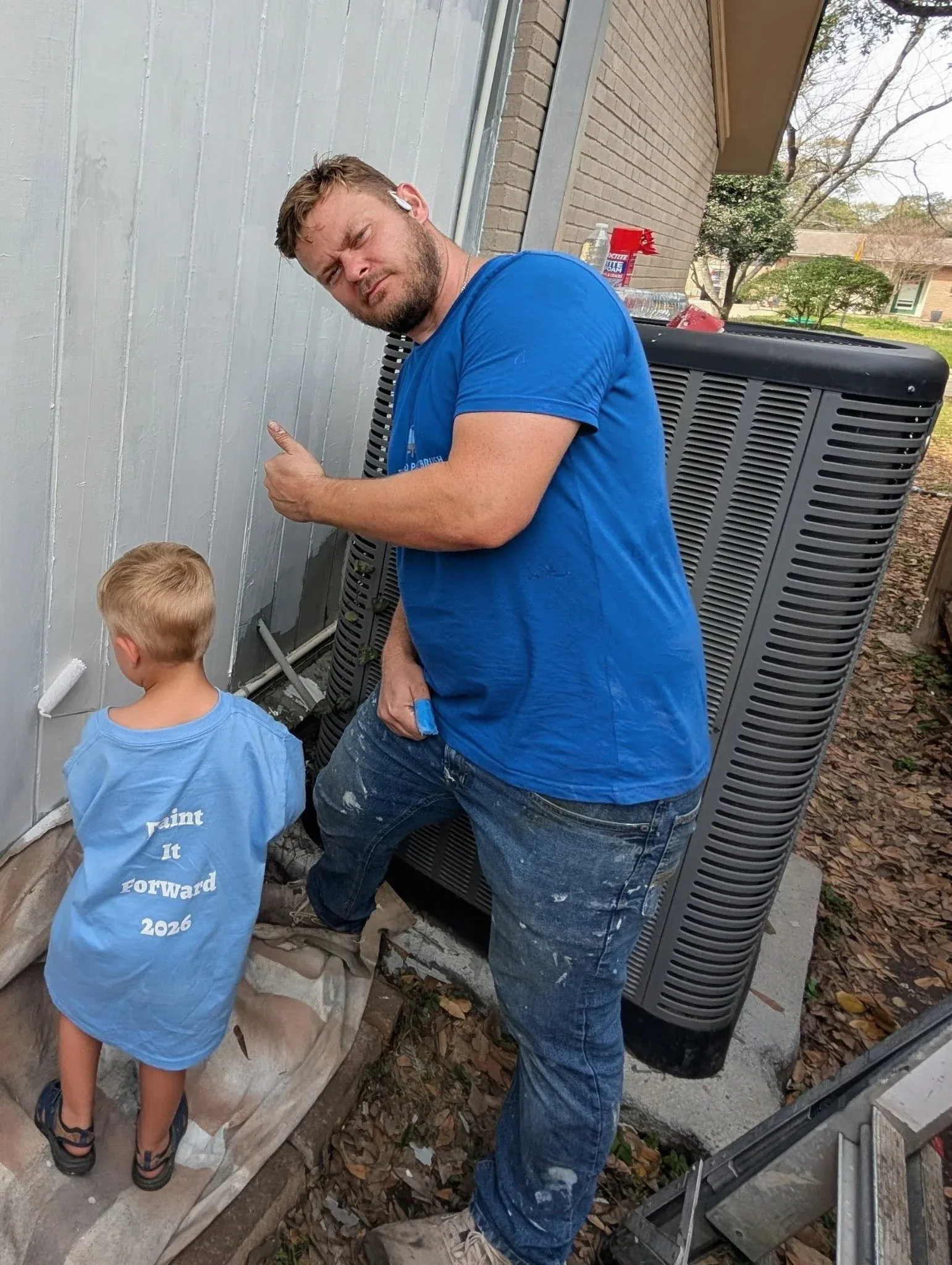 Chris Petkau, owner of The Proud Paintbrush, and his son painting together during Paint It Forward 2026 in West Houston, Texas.